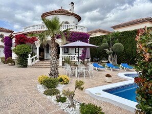 Eine Villa mit Pool, Außenbereich und gepflegtem Garten.