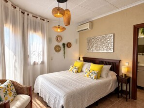 Une chambre avec un grand lit, deux lampes de chevet, un climatiseur fixé au mur et un élément décoratif mural.