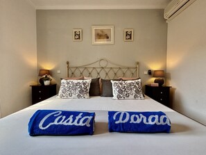 Ein Schlafzimmer mit einem Bett, zwei Nachttischen, einem Kopfteil und drei gerahmten Bildern an der Wand.