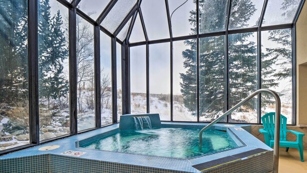 Ein gläsernes Whirlpool mit Blick auf schneebedeckte Bäume und eine felsige Landschaft.