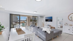 Een moderne woonkamer met een eetgedeelte, grote ramen en uitzicht op de stad.