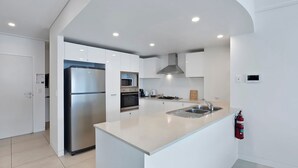 Een moderne keuken met een roestvrijstalen koelkast, een ingebouwde oven, magnetron en een gasfornuis.