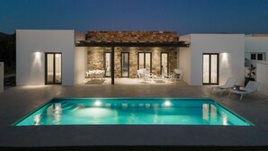 Ein modernes Haus mit Swimmingpool, Sitzgelegenheit im Freien und einer Steinsäule.