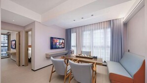 A modern living room with a dining area, a sofa, and a TV mounted on the wall. - Maple, Longyan, Wanda Plaza (Longyan)
