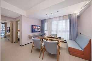 Una sala moderna con comedor, un sofá y un televisor en la pared.