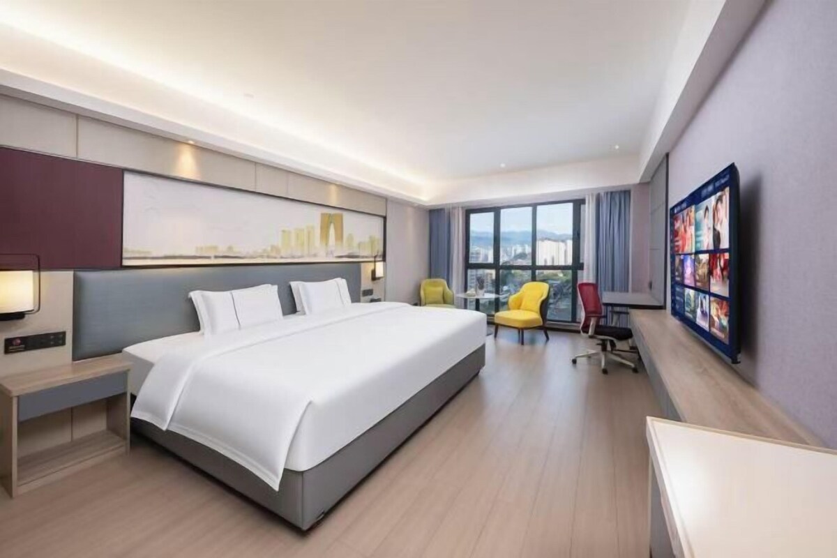 Una habitación de hotel moderna con una cama grande, un escritorio, una silla y un televisor.