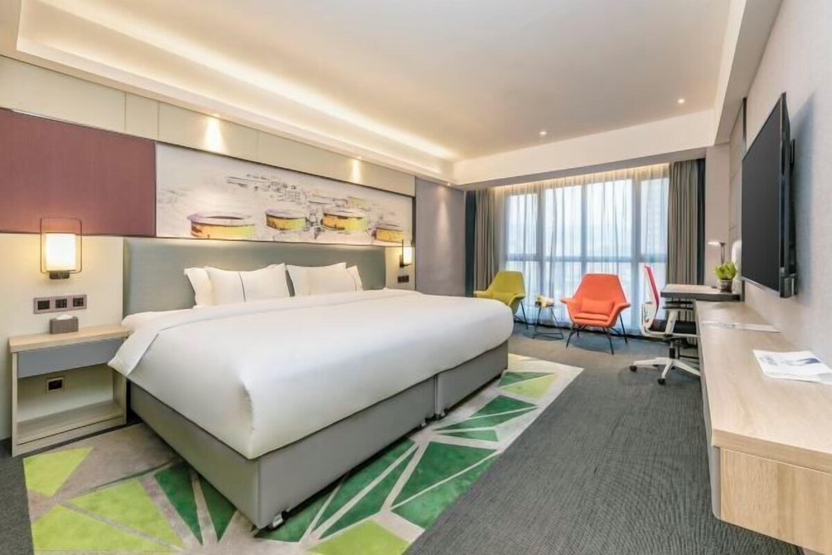 A modern hotel room with a large bed, a desk, and a chair.