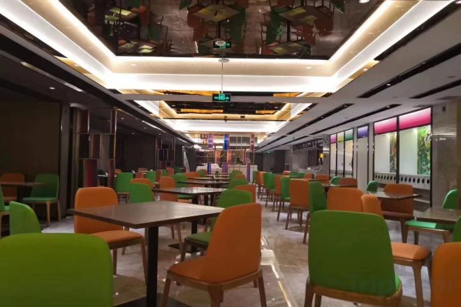 Un espace repas avec des tables et des chaises, un plafond éclairé et une vue sur l’extérieur.