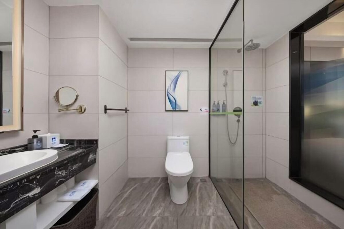 Un baño moderno con inodoro blanco, ducha con cerramiento de vidrio y lavabo de mármol.