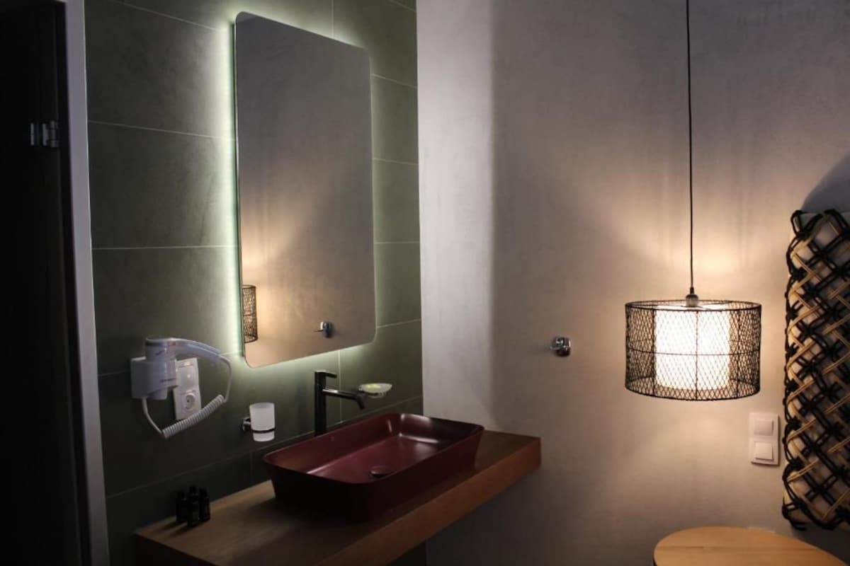 A bathroom with a rectangular sink, a mirror, and a hanging light fixture.