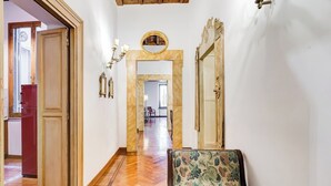 A hallway with a wooden door, a mirror, and a floral chair. - Historical Apartment few steps from Piazza Navona (Roma)