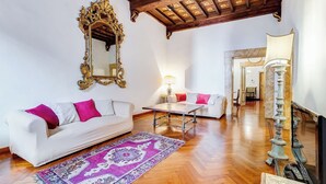 A spacious living room with a white sofa, a patterned rug, and a wooden ceiling. - Historical Apartment few steps from Piazza Navona (Roma)