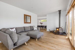 A modern living room with a sectional sofa, a fireplace, and a dining area in the background.