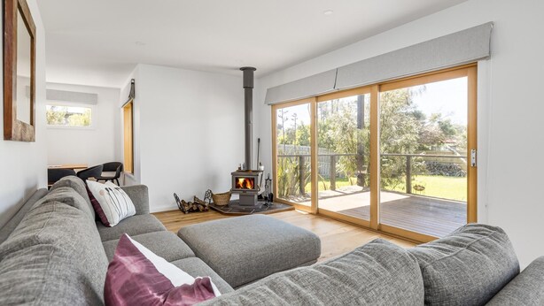A modern living room with a grey sofa, a fireplace, and a sliding glass door leading to a backyard.