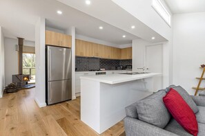 A modern kitchen with a central island, stainless steel appliances, and a built-in fireplace.