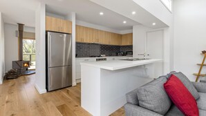 A modern kitchen with a central island, stainless steel appliances, and a black tiled backsplash.