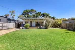 A residential property with a fenced backyard, a covered porch, and a garage.