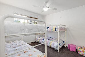 A room with bunk beds, a ceiling fan, and a window.
