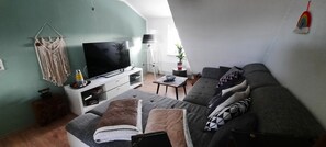 Un salon équipé d’un téléviseur à écran plat, d’un canapé, d’une table basse et d’une lampe.