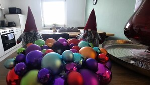 A kitchen with white cabinets, a coffee maker, and a microwave. There are two gnome figures with red hats. - Apartment in a central location (06502 Thale OT Westerhausen)