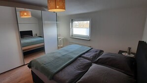 A bedroom with a bed, a wardrobe, a window, and a bedside table. - Apartment in a central location (06502 Thale OT Westerhausen)