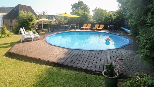 Un patio trasero con piscina, sillas de deck y sombrillas.