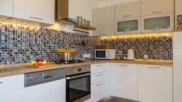 A modern kitchen with white cabinets, a stainless steel range, and a microwave.