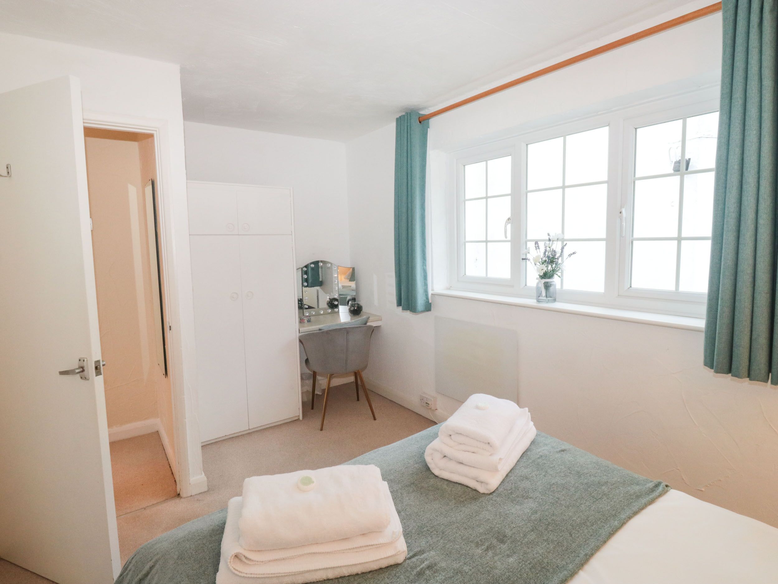 Un dormitorio con cama, escritorio, silla y ventana con cortinas.