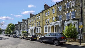 A row of terraced houses with a parked car on the street. - Immaculate 2 Bed Flat in West Kensington (London)