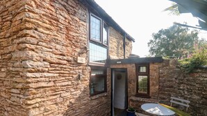A stone building with a small patio area, a door, and a window.
