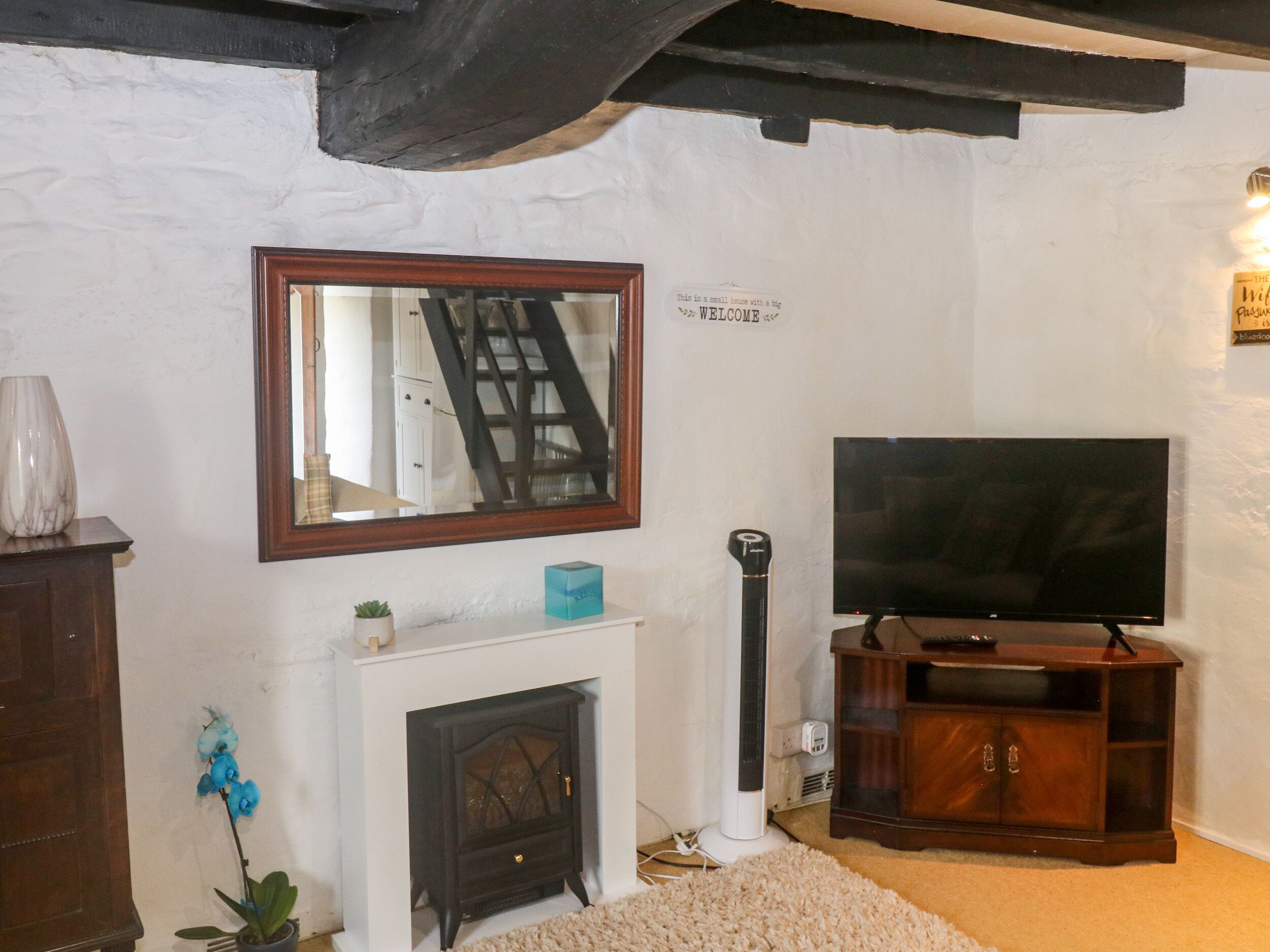 A cozy living room with a fireplace, a television, and a mirror on the wall.