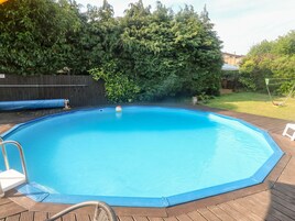 A rectangular swimming pool with a wooden deck surrounding it.
