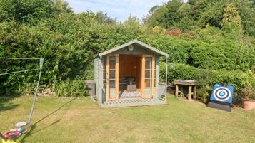 A small wooden cabin with a porch, a target, and a lawnmower.