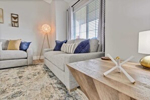 A living room with a sofa, a coffee table, and a floor lamp. - Calming 3 bedroom home with designer details in Na (Nampa)