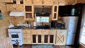 Eine Küche mit Holzausstattung, einem Herd, einer Mikrowelle und einem Kühlschrank.