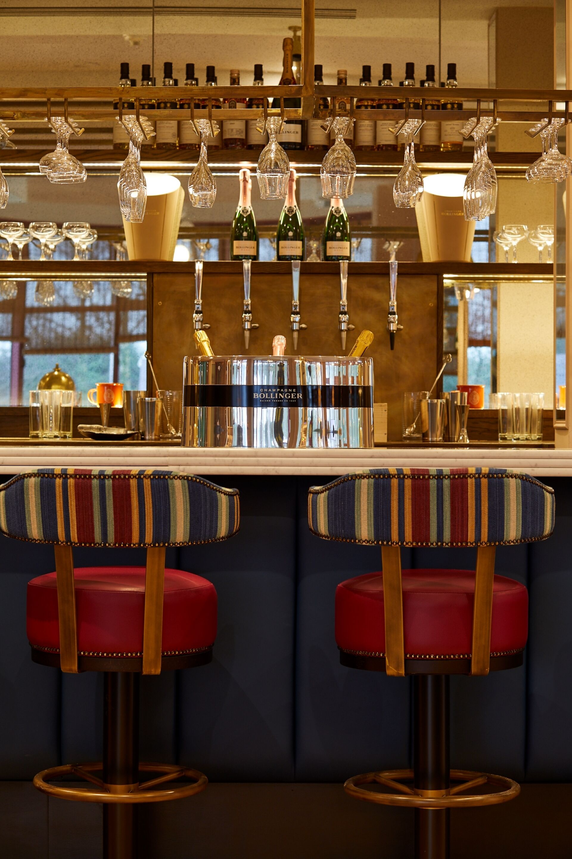 A bar area with two stools, a bottle of champagne, and a bottle of wine.