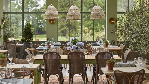A restaurant with wicker chairs and tables, large windows, and hanging wicker lamps. - The Retreat, Elcot Park (Newbury)