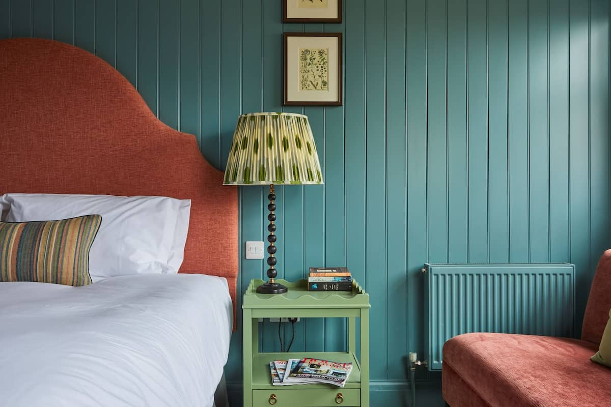 A bedroom with a bed, a nightstand with a lamp, and a radiator.