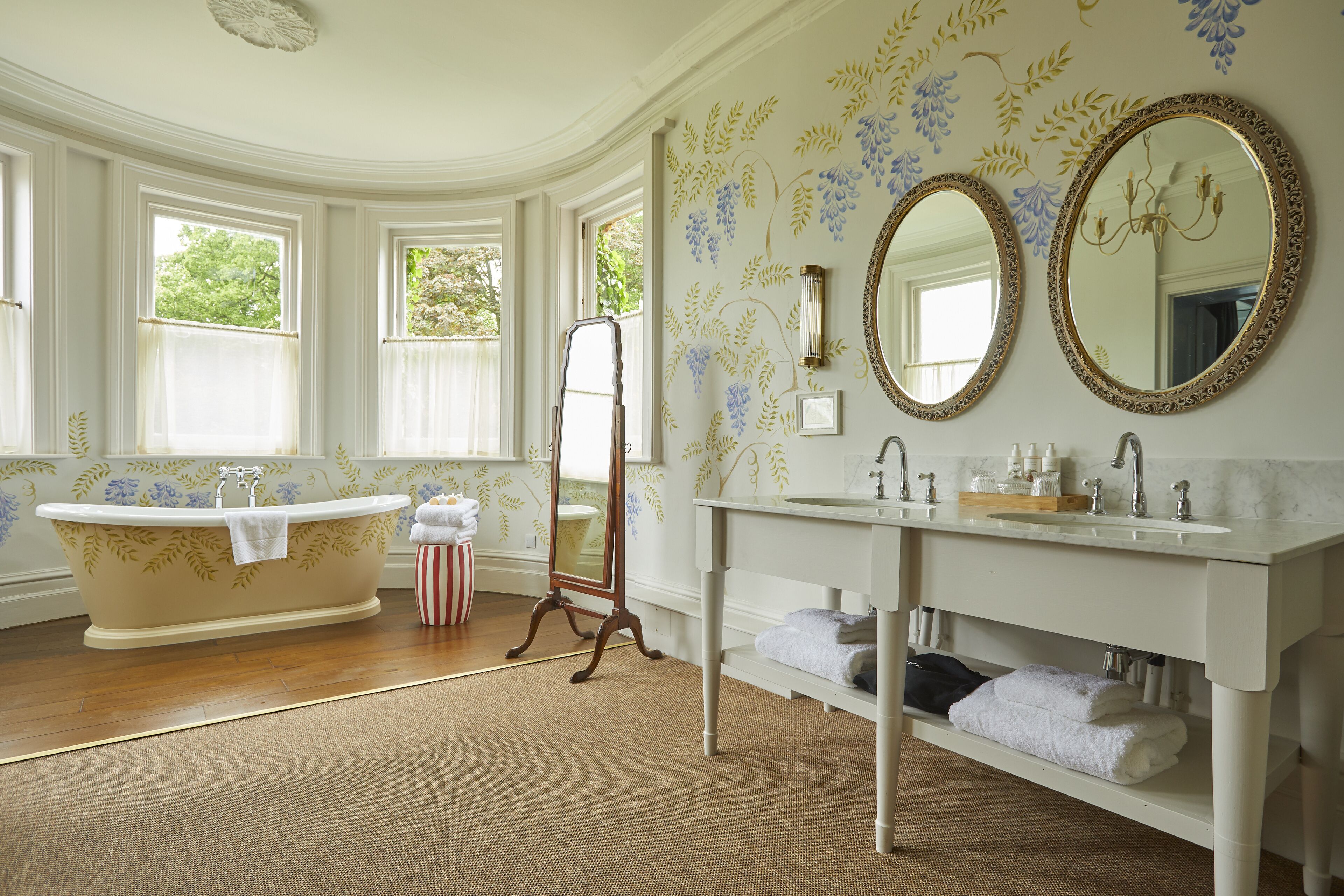 A bathroom with a freestanding bathtub, a vanity with a mirror, and a large window providing natural light.