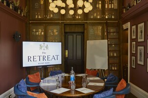 Un salón de conferencias con una mesa redonda, sillas y una pantalla grande que muestra