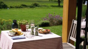 An outdoor dining table with a view of a green field, a bowl of salad, and a pitcher of water. - The Retreat, Elcot Park (Newbury)