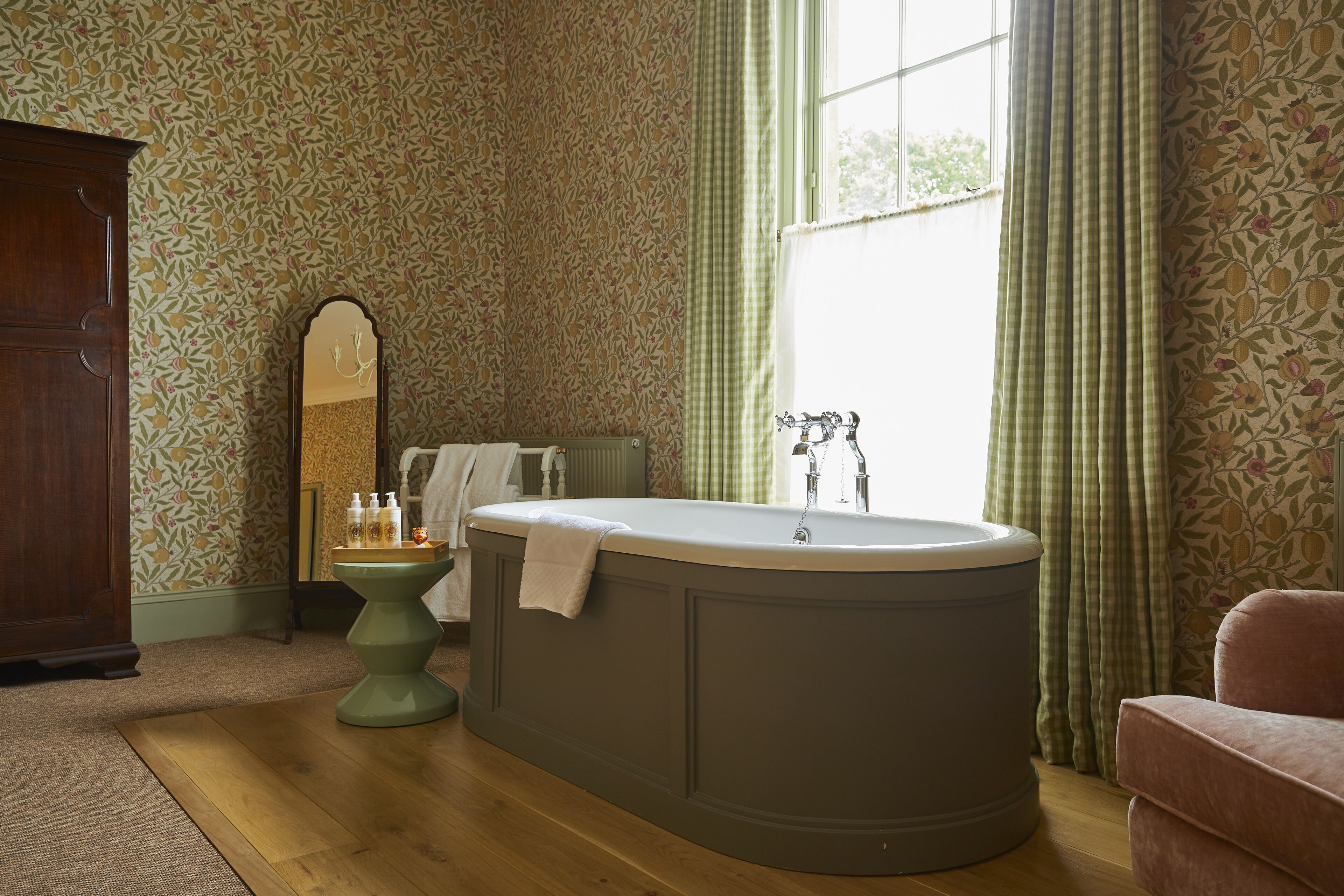 A bathroom with a freestanding bathtub, a pedestal sink, and a mirror.