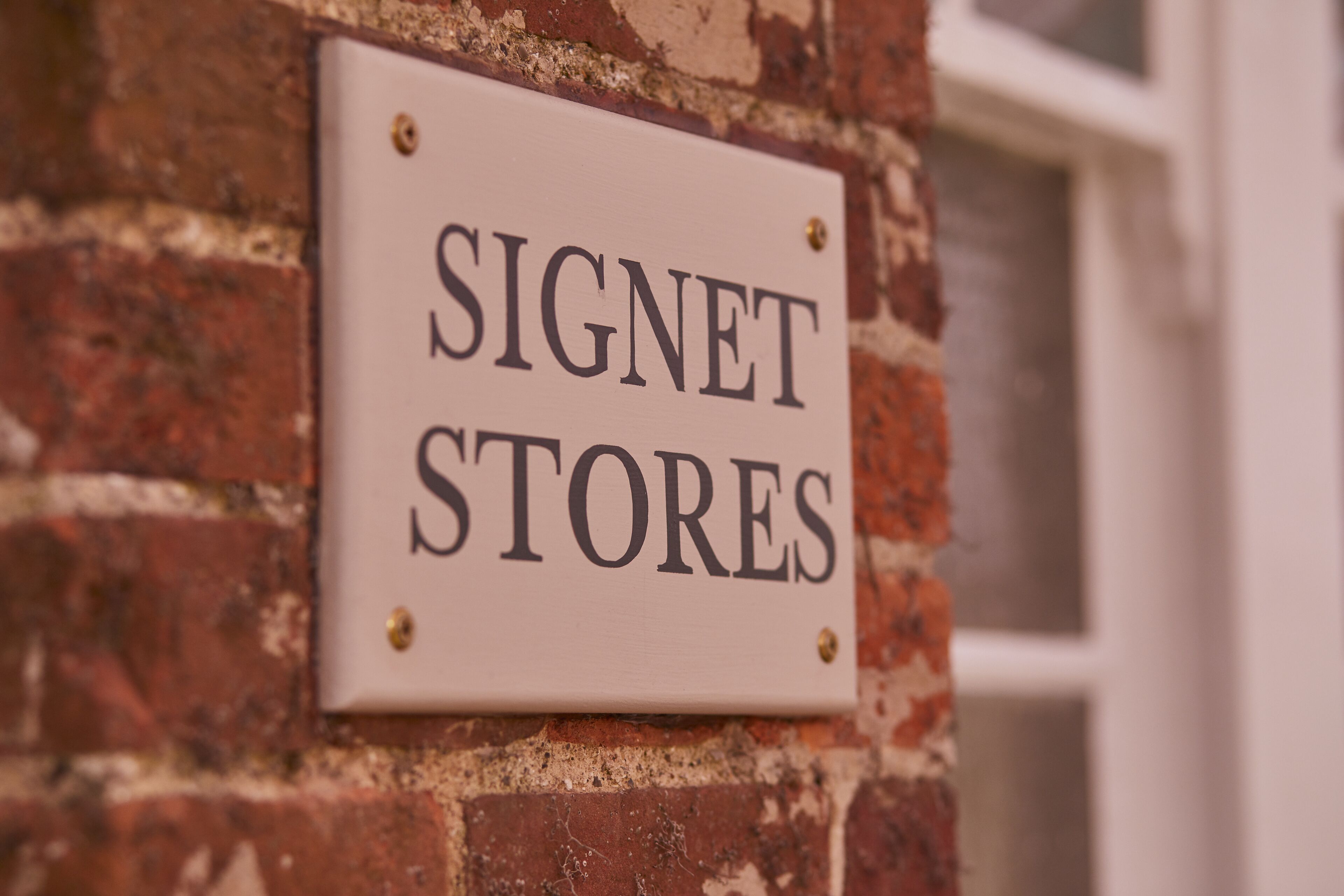 A sign on a brick wall that reads "SIGNET STORES".