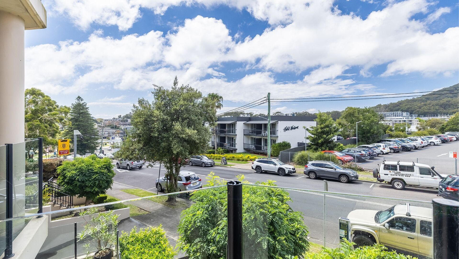 A hotel with a parking lot, a street view, and a clear sky.