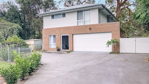 Une maison à deux étages avec un garage, une porte d’entrée et un petit jardin.