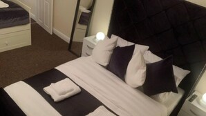 A neatly made bed with white and dark pillows, a white blanket, and two folded towels on a dark-colored bedspread. - "the Old Forge"- 5 Minutes Away From Motorway (Bradford)