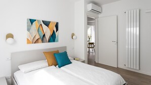 Ein Schlafzimmer mit einem Bett, einem Gemälde, einer Klimaanlage und einem Kleiderschrank.
