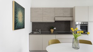 Eine moderne Küche mit weißen Schränken, einer Marmor-Spritzschutzwand, einem eingebauten Backofen und einem Essbereich mit Tisch und Stühlen.