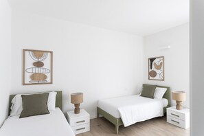 A minimalist bedroom with two beds, white bedding, and wooden headboards. - Maison Bellini 4 with pool and near to the lake (Toscolano-Maderno)