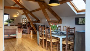 A dining area with wooden chairs and a table set for six, a wooden ceiling with exposed beams, and a skylight above. - Granary at Rectory Farm - sleeps 5 guests  in 3 bedrooms (Shipston-on-Stour)